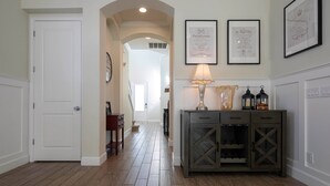 Un couloir avec une porte blanche, un plancher en bois, une lampe et des certificats encadrés accrochés au mur.
