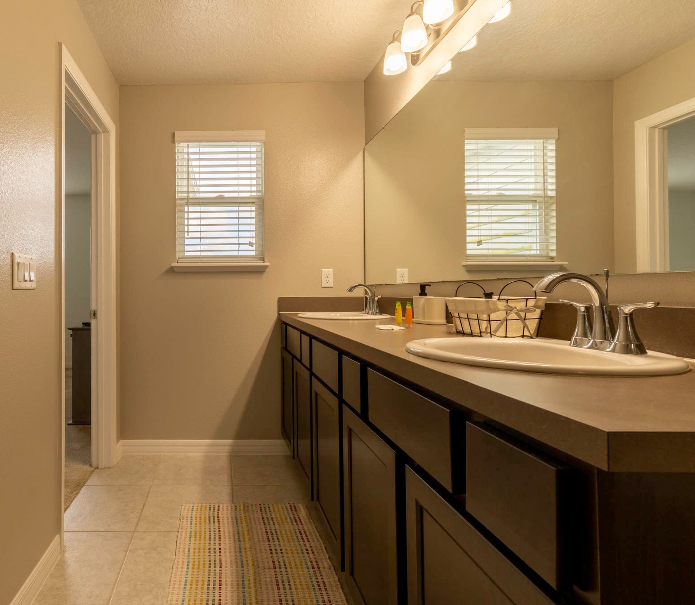 A bathroom with two sinks, a large mirror, and a walk-in shower.
