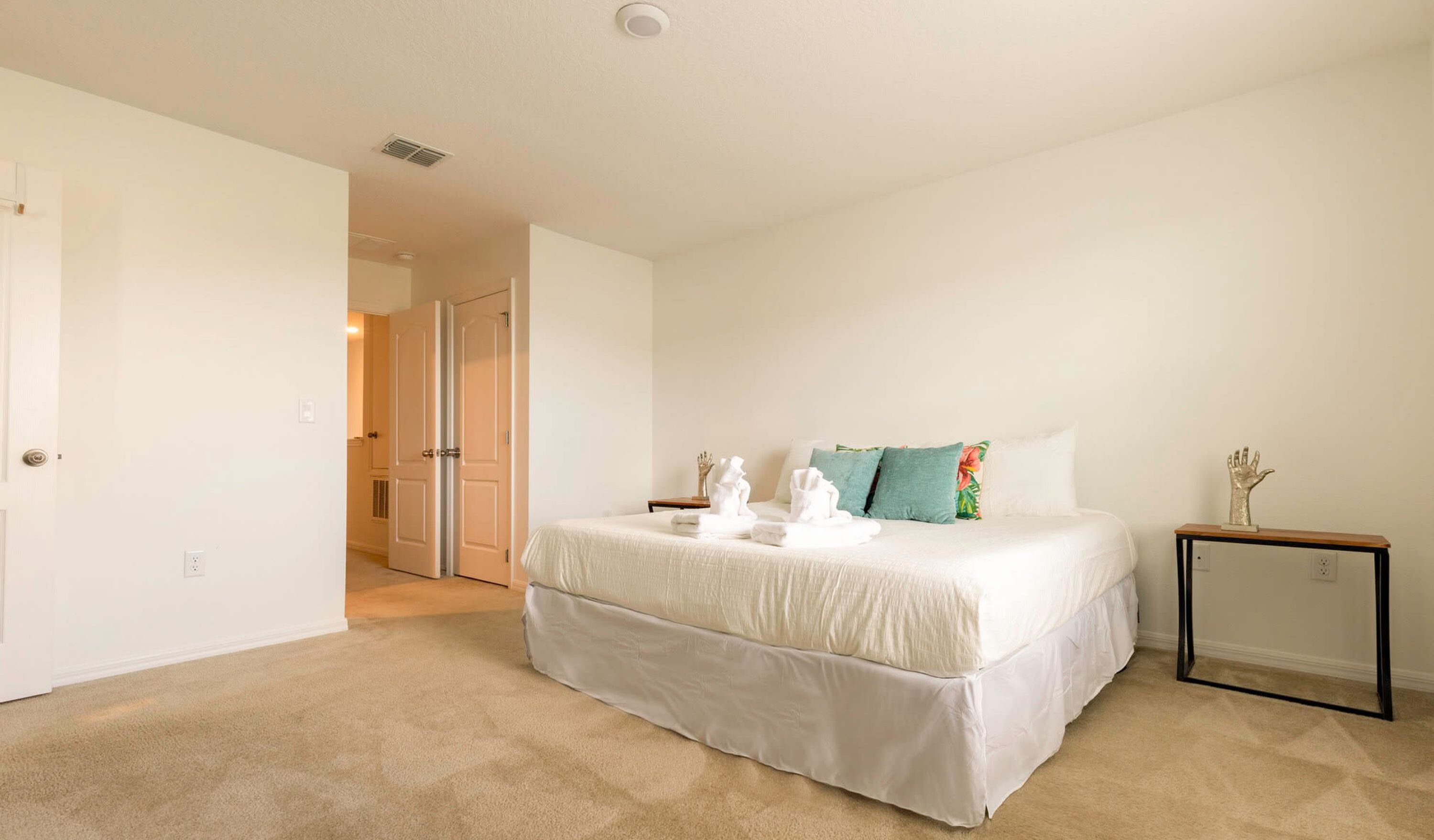 Un dormitorio con cama, mesita de noche y puerta que da a otra habitación.