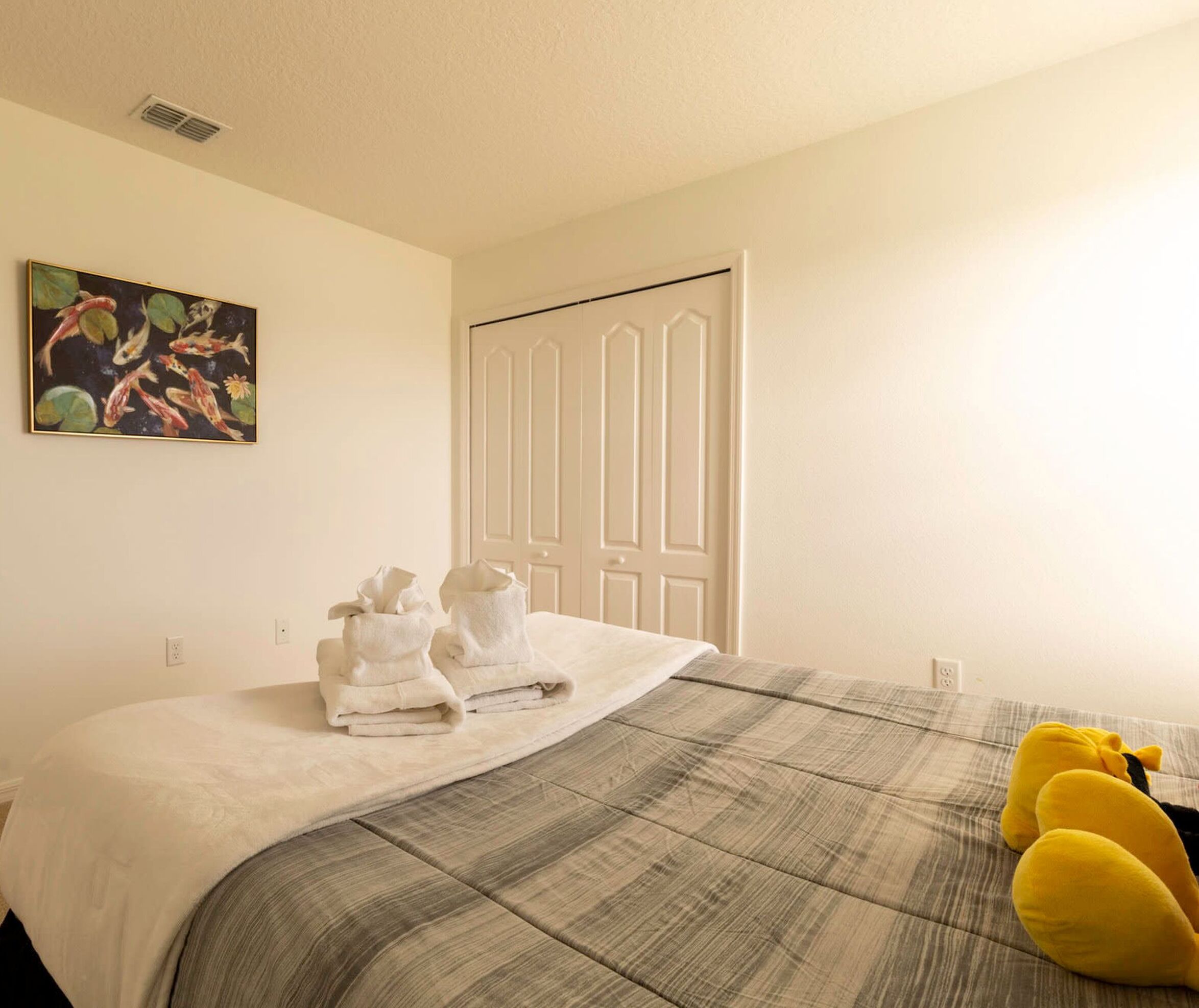 A hotel room with a bed, a painting, and a door.
