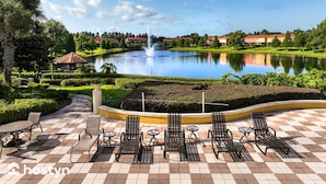 A courtyard with a fountain, outdoor seating, and a view of a lake and buildings in the background. - Townhome Jacuzzi Grill 10 min Disney (Kissimmee)