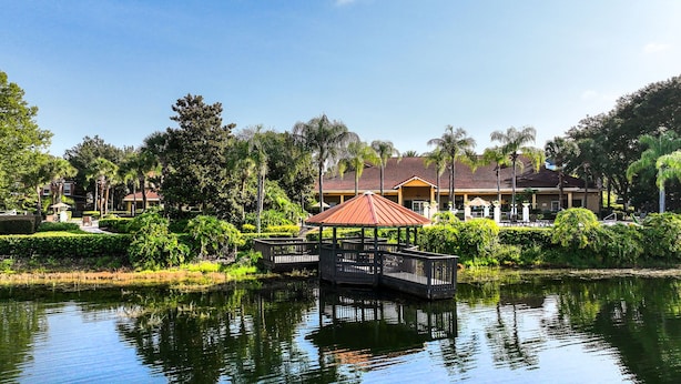 A serene hotel setting with a water body, a gazebo, and lush greenery. - Townhome Jacuzzi Grill 10 min Disney (Kissimmee)