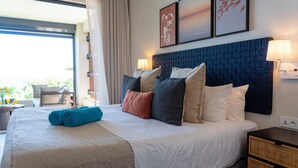 A hotel room with a large bed, a bedside table, a lamp, and artwork on the wall. - Beach and Mountain by Horizon Holidays (Black River)