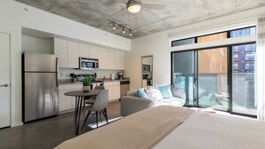 A modern kitchen with a refrigerator, microwave, and dining area. - Roosevelt Point (Phoenix)