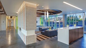 A modern lobby with a central seating area, a large column, and a view of the outdoors. - Roosevelt Point (Phoenix)