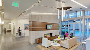 A modern indoor space with a fireplace, seating areas, and a large window overlooking a pool. - Roosevelt Point (Phoenix)