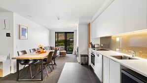 Een moderne keuken met witte kasten, een ingebouwde oven en een groot eiland met een spoelbak.