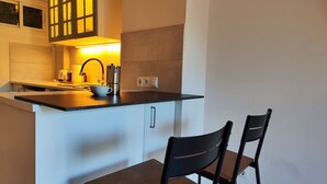 A compact kitchen with a dark countertop, a coffee maker, and a kettle. There are two chairs and a small table. - Pretty Studio With Sea View Agata (Benalmádena)