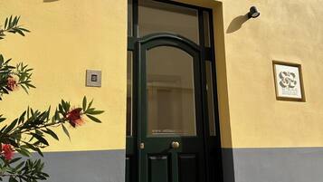 Un edificio con una porta verde, un numero 57 sopra e una piccola finestra con un apparecchio di illuminazione.