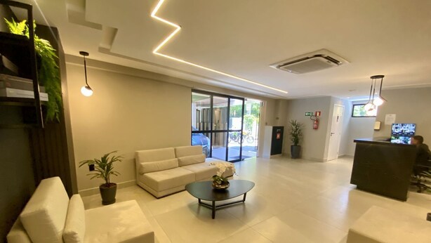 Un hall d’entrée spacieux au design moderne, comprenant un ensemble de canapés, une table basse et un comptoir d’accueil.