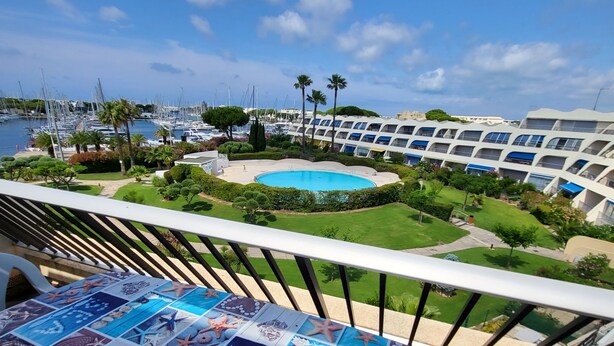 Un balcón con vista a un puerto deportivo, una piscina y un edificio de hotel.
