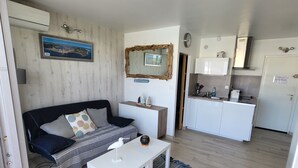 Una sala de estar con un sofá, una mesa de centro y una cocina con armarios y electrodomésticos.