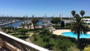 Un puerto deportivo con numerosas embarcaciones amarradas, una piscina y palmeras.