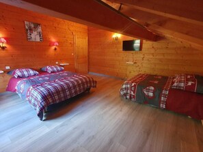 A cozy room with two beds, wooden walls, a mounted TV, and wall-mounted lights. - Chalet for 12 people, 300m from the Vonnes chairlift - Chatel Reservation (Châtel)