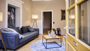 A living room with a grey sofa, a wooden coffee table with flowers, and a round rug. - Gutshaus Suite #3 "emma" im Weingut Fitz-ritter - Vdp/biozertifiziert (Bad Dürkheim)