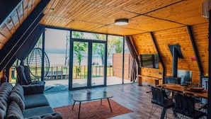 Amplia sala de estar con techo alto, vigas de madera, un sofá grande y una mesa de comedor.