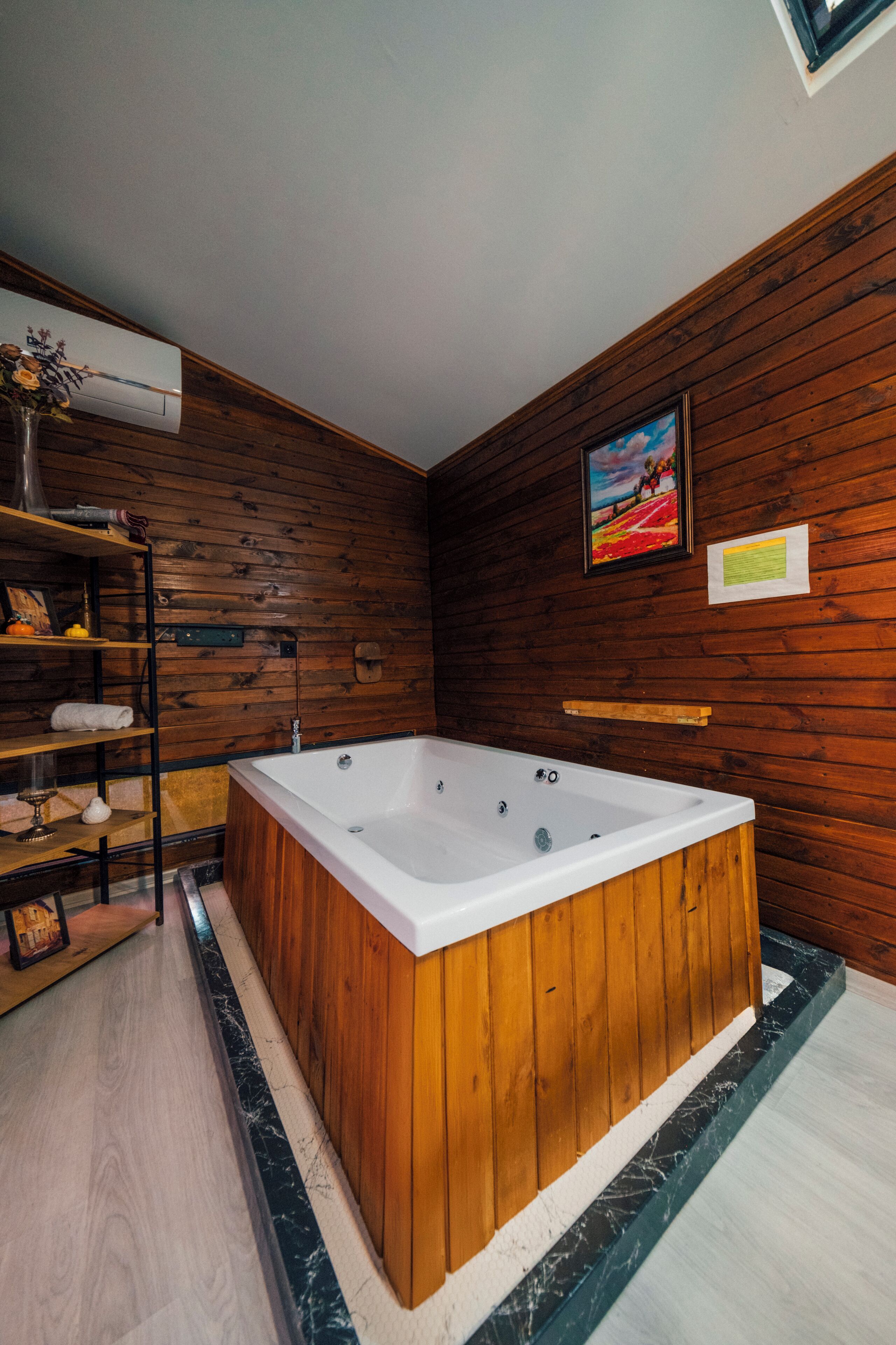 Un baño moderno con paneles de madera, una bañera independiente grande y un estante con toallas.