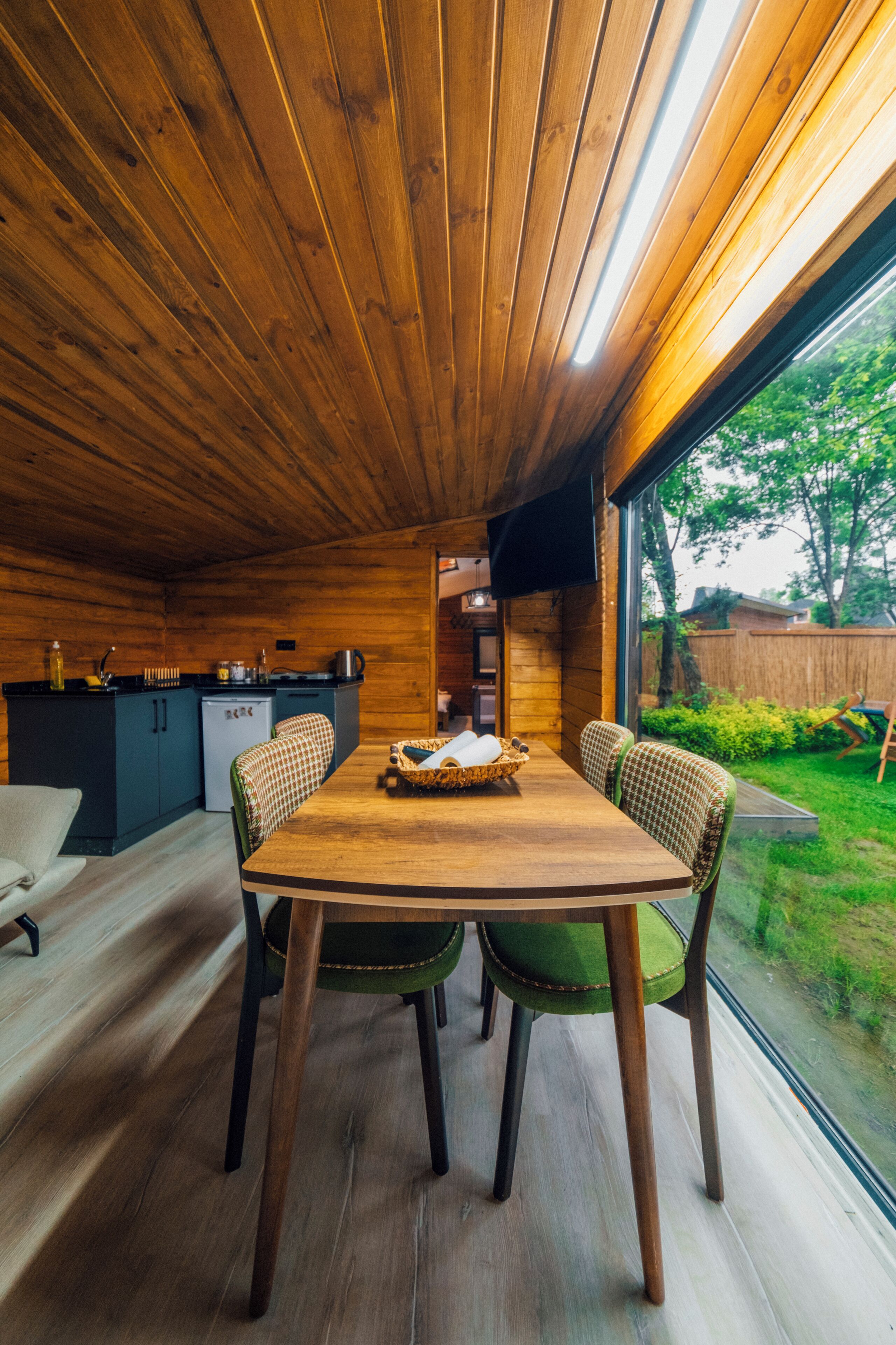 A wooden interior with a dining table, chairs, and a kitchen area.