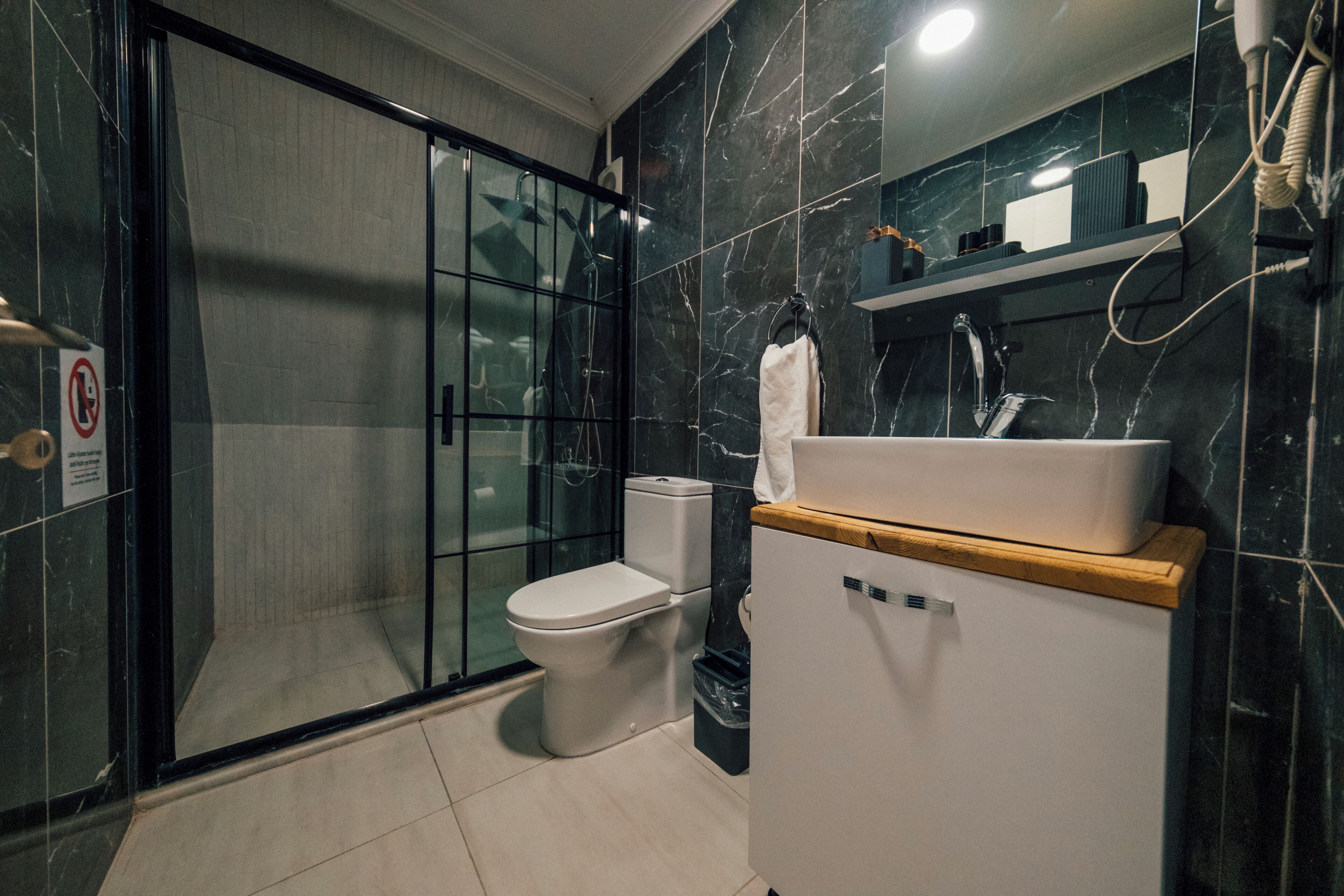 Une salle de bain moderne avec une douche à parois de verre, des toilettes blanches et un lavabo doté d'un plan de travail en bois.