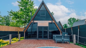 Una casa moderna con piscina, terraza de madera y puerta de entrada de cristal.