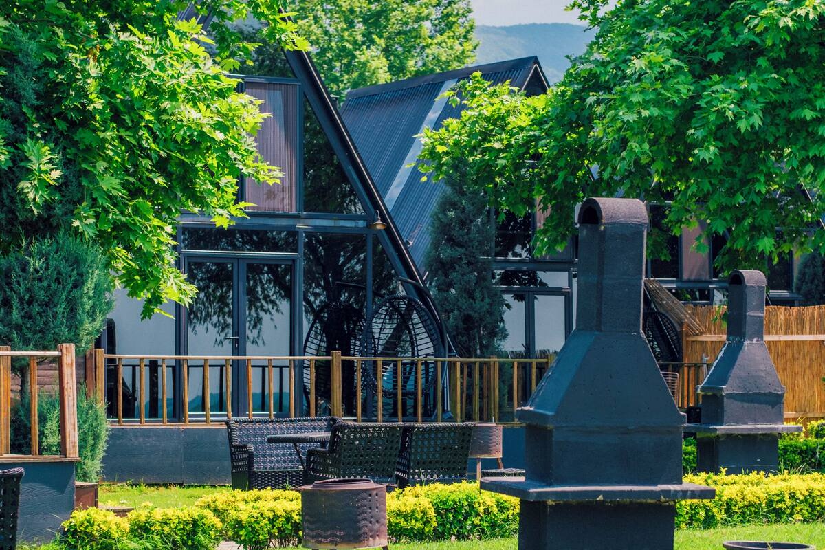 A cemetery with headstones, a wooden fence, and a modern building in the background.