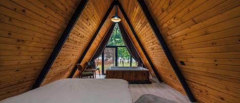 Un dormitorio de buhardilla acogedor, con una cama grande, una mesita pequeña y vistas al exterior a través de una ventana.