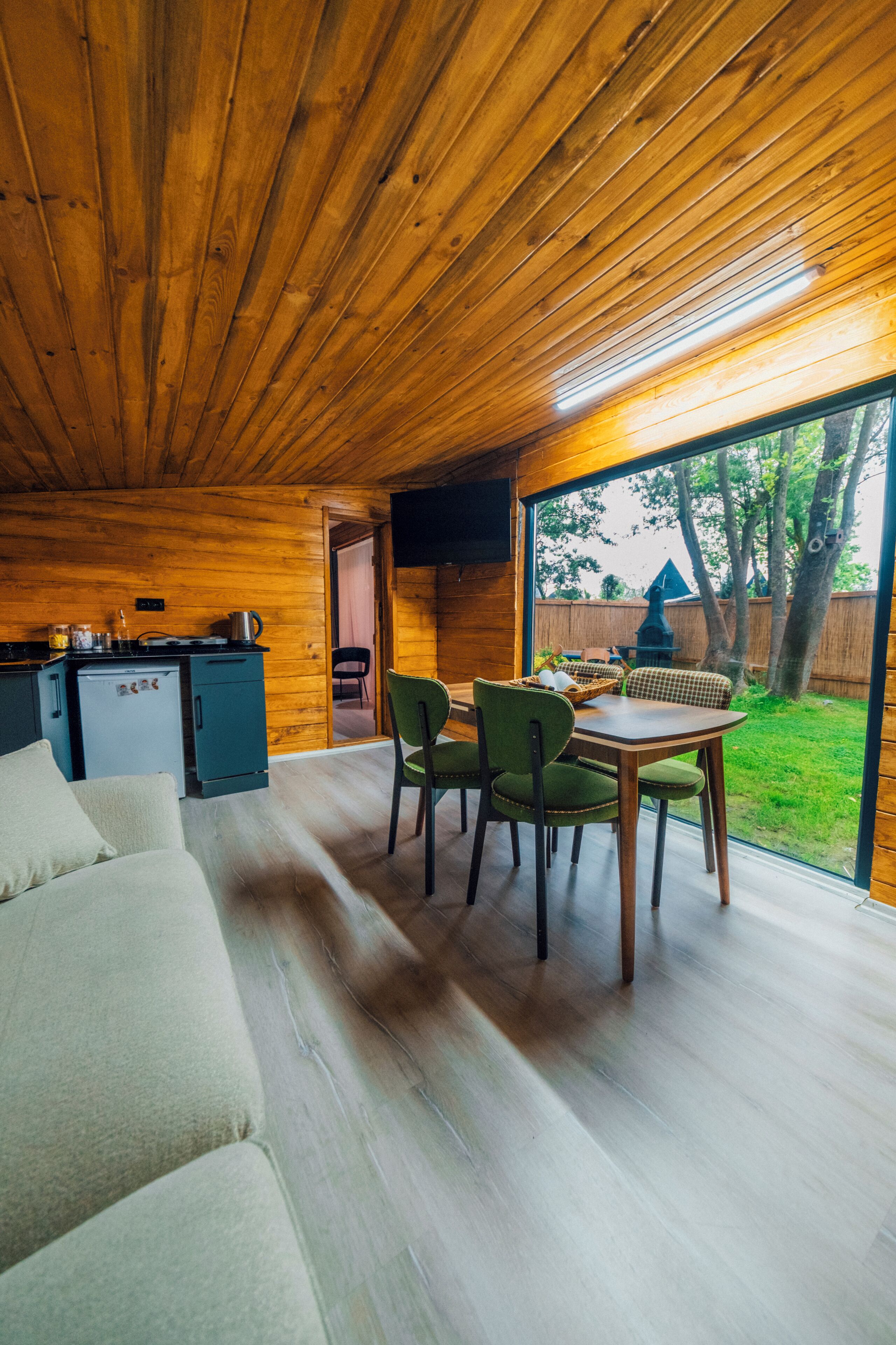 L’intérieur d’un chalet en bois comprend un coin repas, une cuisine et offre une vue sur l’extérieur.