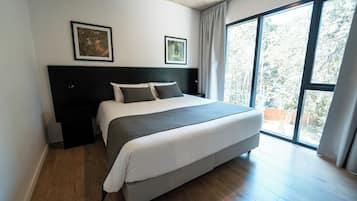 Um quarto moderno com uma cama grande, uma cabeceira escura e duas fotos emolduradas na parede.