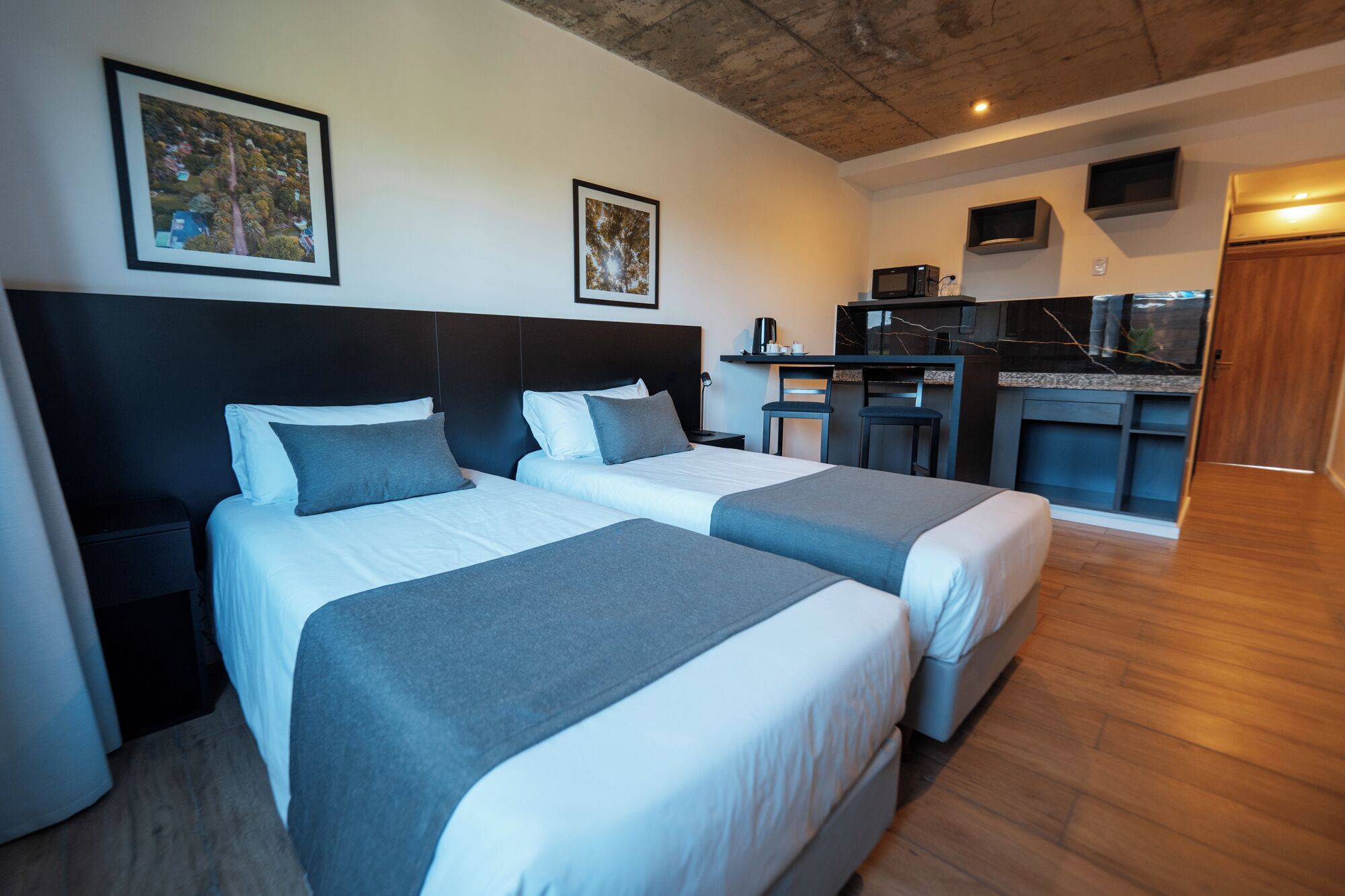 A hotel room with two beds, a desk, a chair, a microwave, and a TV.