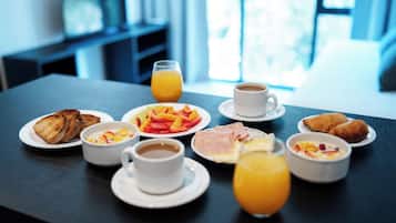 A breakfast table with toast, fruit, pastries, coffee, and orange juice.
