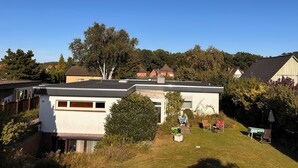 A modern house with a flat roof, a small attached garage, and a well-maintained lawn.