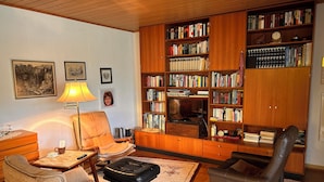 A cozy living room with a fireplace, a bookshelf filled with books, a comfortable sofa, and a coffee table.