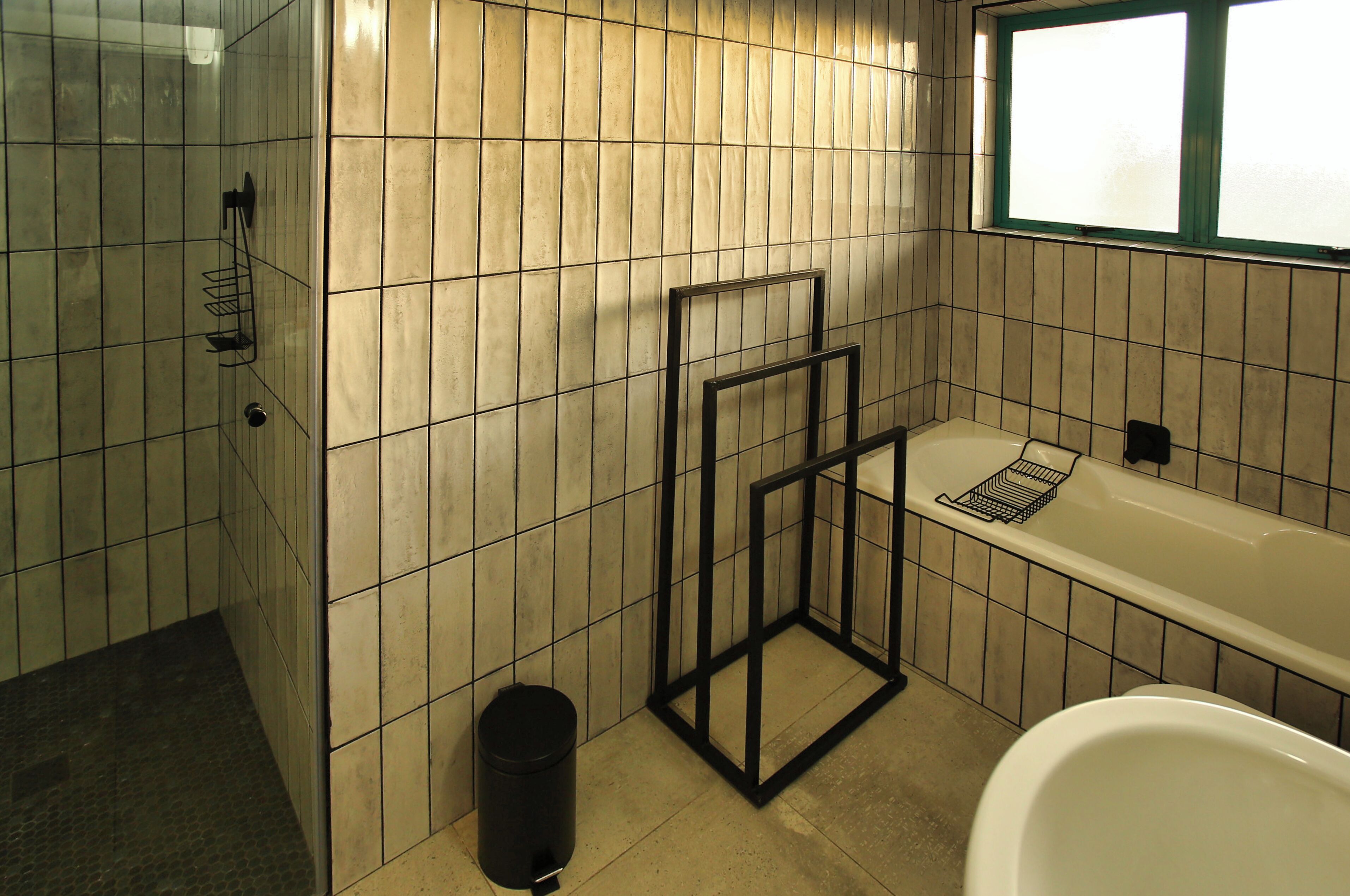 Un baño con bañera, zona de ducha y ventana.