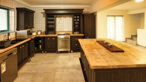 A modern kitchen with dark cabinetry, a central island, and a built-in oven. - The Spry House, Langebaan, 8 Sleeper (Langebaan)
