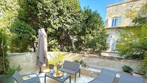 Une terrasse extérieure avec une table, des chaises et des fauteuils de jardin.