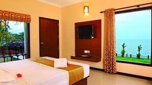 Une chambre d’hôtel avec un lit, une télévision, un ventilateur de plafond et une vue sur la mer.