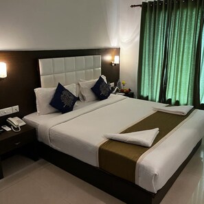 Relax in comfort with a neatly made bed, featuring a duvet and decorative pillows, and enjoy the convenience of a bedside table with a telephone.