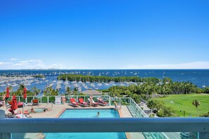Un espace piscine avec des chaises longues et vue sur le port de plaisance.