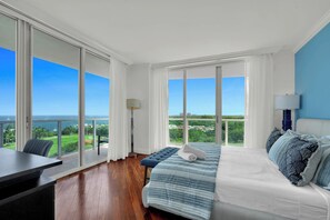 A bedroom with a large bed, a desk, and a view of the ocean. - Fabulous 2-Bedroom in the Heart of Grove (Miami)