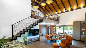A spacious living area with a high ceiling, a staircase with a metal railing, and a dining area with orange chairs and a long table. - Luxury Villa Meden Dol with heated pool, Hot-Tub, 2 Saunas (Skradin)