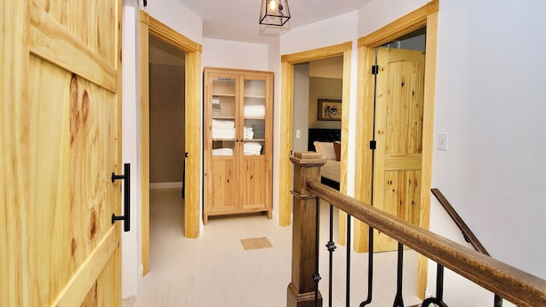 A wooden interior hallway with a staircase, a wooden wardrobe, and a cabinet with glass doors. - Riverfront Luxury w/ Fire Pit & Chef's Kitchen (Bolingbrook)