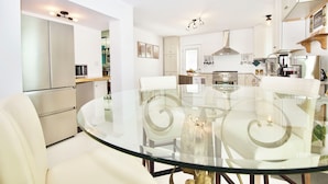 A modern kitchen with white cabinets, a glass dining table, and stainless steel appliances. - Riverfront Luxury w/ Fire Pit & Chef's Kitchen (Bolingbrook)