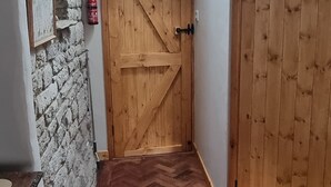 Een hal met een houten deur, een stenen muur en een visgraatvloer.