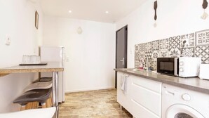 A compact kitchen with a microwave, toaster, and a washing machine.