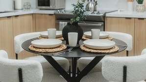 Un coin repas avec une table ronde, quatre chaises et un vase avec une plante.