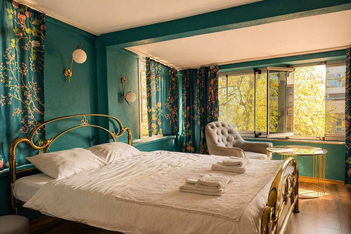 Un dormitorio con cama, una silla, una mesita y cortinas.