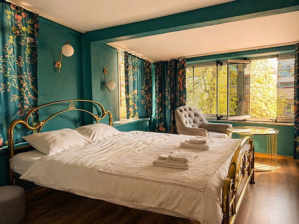 A bedroom with a bed, a chair, a small table, and curtains.
