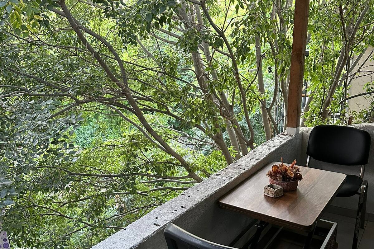 Un balcón con mesa y sillas, con vista a un paisaje verde y exuberante.
