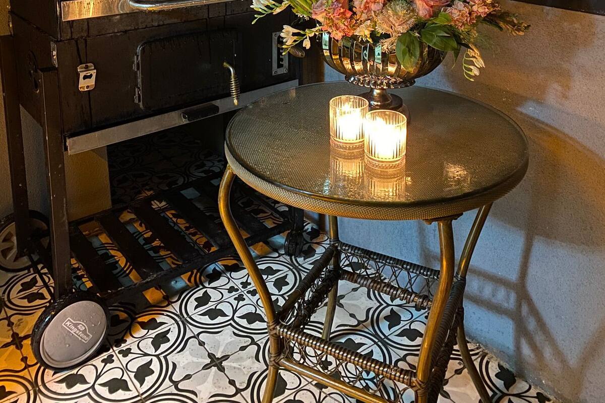 Una terraza en la azotea con una parrilla, una mesa con velas y un florero decorativo.