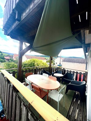 An outdoor seating area with a table and chairs, a wooden deck, and a view of the countryside. - Au Coeur du Vignoble, Magnifique vue Avec Terrasse (Westhalten)